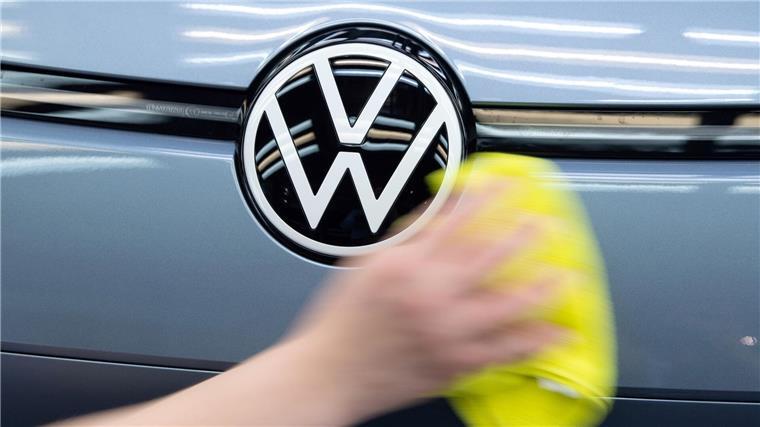 Ein Mitarbeiter von Volkswagen streicht mit einem Tuch über ein Fahrzeug von VW.