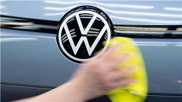 Ein Mitarbeiter von Volkswagen streicht mit einem Tuch über ein Fahrzeug von VW.