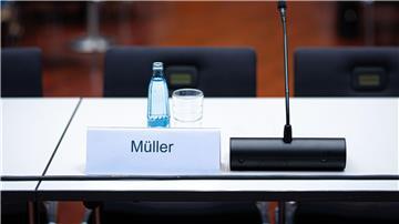 Ein Namensschild mit der Aufschrift „Müller“ steht auf einem Tisch.