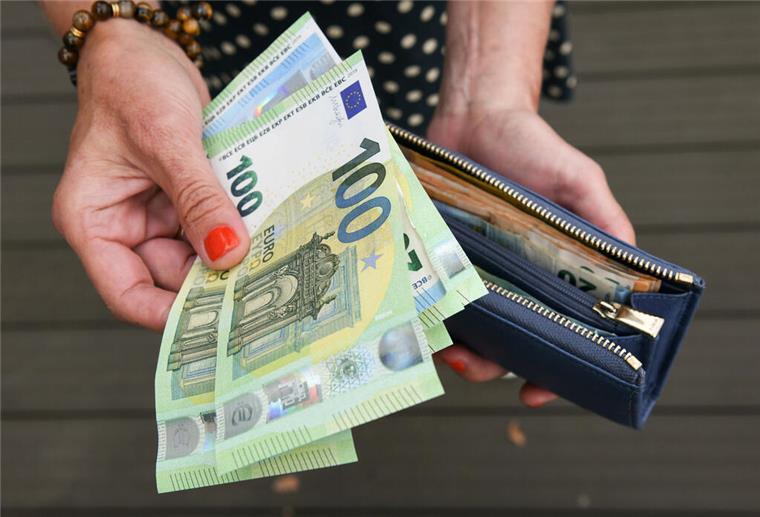 Durchgesickert: Neuer Mega-Zuschuss verspricht bis zu 1800 Euro pro Monat für Familien Eine Frau hält eine mit mehreren Geldscheinen gefüllte Geldbörse in einer Hand