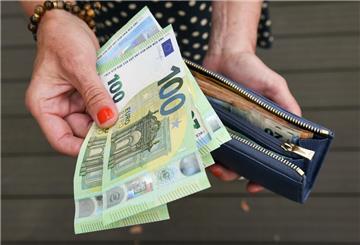 Eine Frau hält eine mit mehreren Geldscheinen gefüllte Geldbörse in einer Hand
