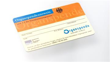 Ein Organspendeausweis spiegelt sich in einem Glastisch.