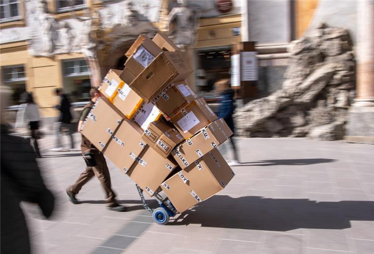 Ein Paketzulieferer transportiert mit einer Sackkarre mehrere Pakete. 