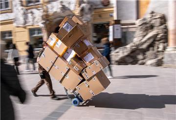 Ein Paketzulieferer transportiert mit einer Sackkarre mehrere Pakete. 