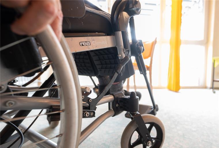 Ein Mann sitzt im Alten- und Pflegeheim Anlagenring in einem Rollstuhl, an dem die Bremse angezogen ist
