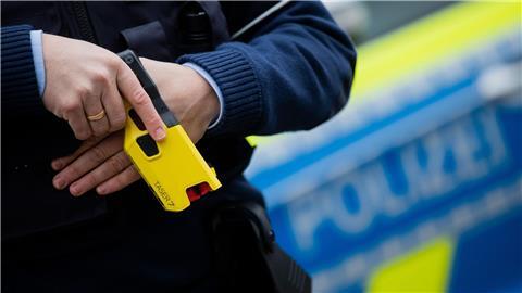 Ein Polizeibeamter hält ein Distanzelektroimpulsgerät (DEIG oder auch Taser).