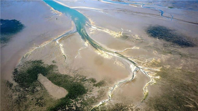 Ein Priel zieht sich durch das ostfriesische Wattenmeer.