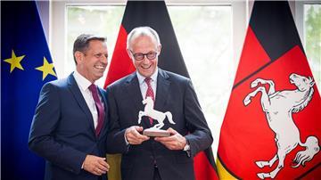 Ein Ross für den Kanzler: Lies (l) überreicht Merz eine Pferdeskulptur – passend zur Krawatte mit Landeswappen-Motiv.