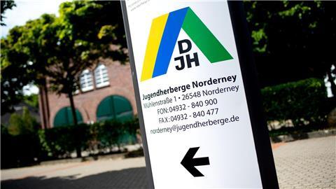 Ein Schild mit dem Logo des DJH steht vor einer Jugendherberge im Norderney.