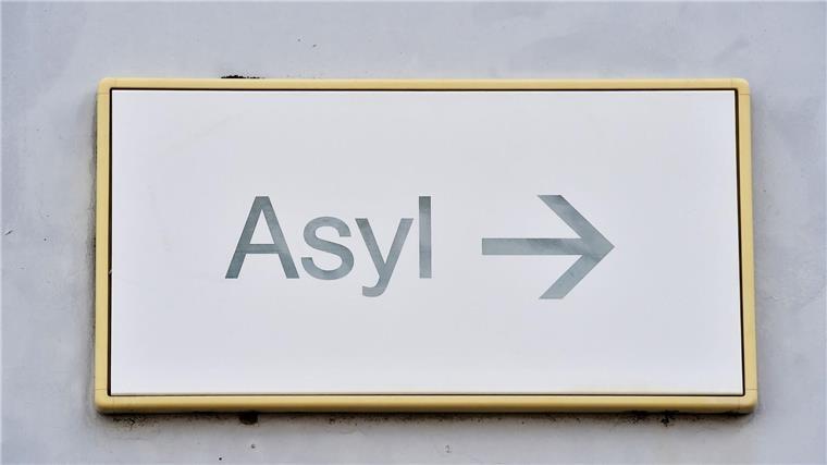 Ein Schild mit der Aufschrift „Asyl“ hängt an einer Wand.
