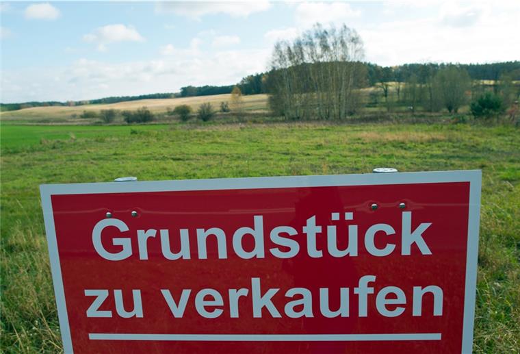 Ein Schild mit der Aufschrift „Grundstück zu verkaufen" steht an einer Straße.