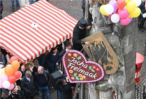 Ein Schornsteinfeger hängen dem Bremer Roland ein Lebkuchenherz um.
