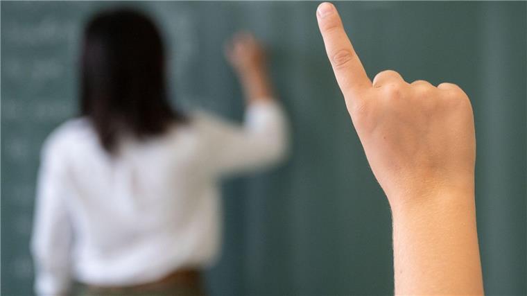 Sonderzulage für verschuldeten Lehrer darf gepfändet werden Ein Schüler meldet sich, während die Lehrerin an die Tafel schreibt.