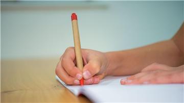 Ein Schüler schreibt mit einem Kugelschreiber in sein Heft.
