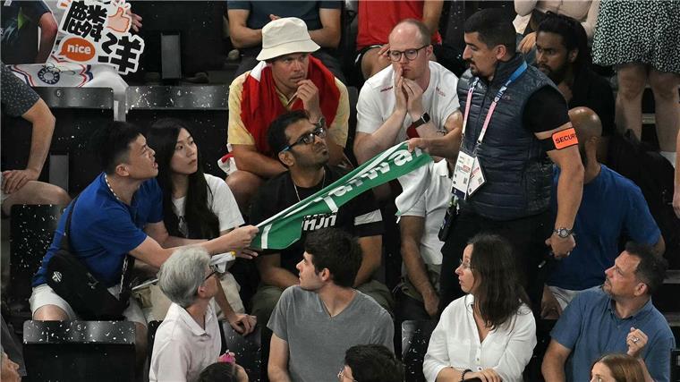 Ein Sicherheitsmann entfernt ein Transparent mit der Aufschrift „Taiwan“ beim Badminton.