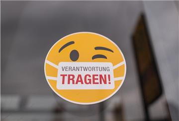 Ein Smiley-Aufkleber mit einem Mundschutz und der Aufschrift „Verantwortung tragen" klebt an einer Scheibe einer Straßenbahn.