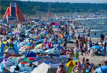 Touristen halten sich bei Sonne und hochsommerlichen Temperaturen im Ostseebad am Strand und im Wasser auf.
