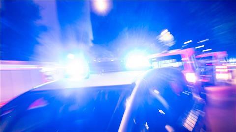 Ein Streifenwagen der Polizei steht mit Blaulicht an einem Einsatzort.