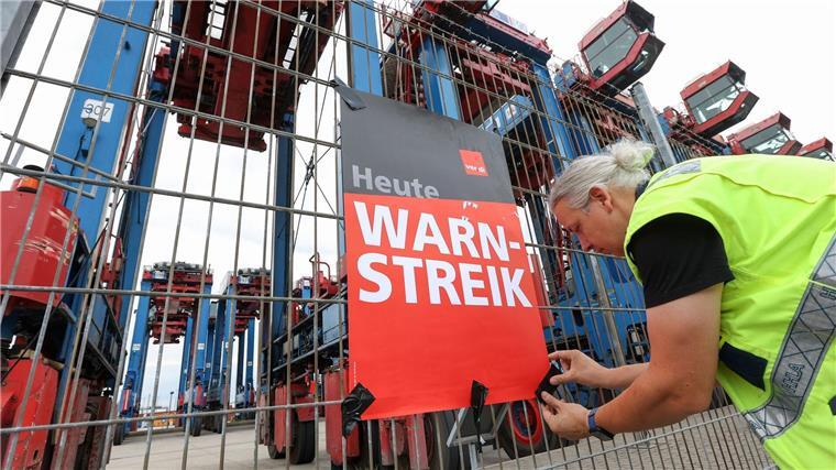 Ein Streikender hängt ein Plakat am Hamburger Hafen auf. (Archivfoto)