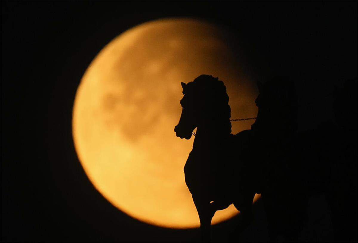 Ein Supermond erhebt sich hinter einer Pferdestatue auf dem Triumphbogen in Moskau während einer partiellen Mondfinsternis.