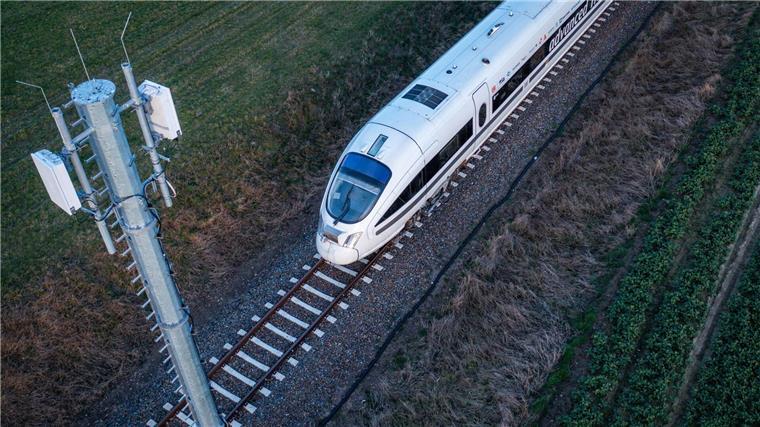 Mobilfunk auf Reisen: Start von 5G-Testfahrten an Zugstrecke Ein Testzug der Deutschen Bahn fährt an einer der Antennenmasten für das 5G-Bahnprojekt vorbei.