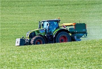 Ein Traktor mit einem Streuaufsatz verteilt Dünger auf einem Feld. Viele Landwirte haben mit massiv gestiegenen Kosten für Düngemittel zu kämpfen.