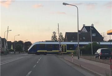Ein Triebwagen der EVB fährt bei geöffneter Schranke über einen Bahnübergang an der B73 in Cuxhaven.