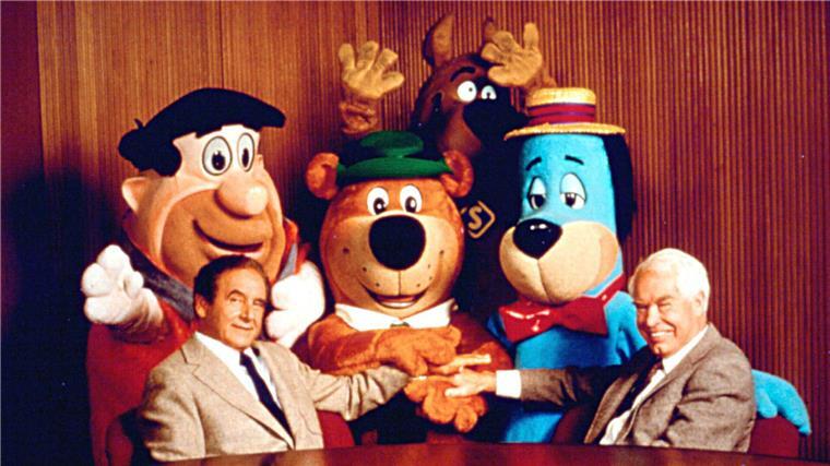 Die Schöpfer der Zeichentrick-Serie "Familie Feuerstein", Joseph Barbera und William Hanna sitzen vor den Figuren aus der Serie. 