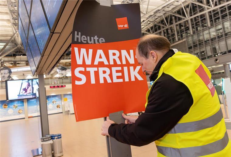 Ein Verdi-Vertreter hängt ein Plakat mit der Aufschrift «Warnstreik» in einem Terminal im Hamburger Flughafen auf.