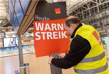 Ein Verdi-Vertreter hängt ein Plakat mit der Aufschrift «Warnstreik» in einem Terminal im Hamburger Flughafen auf.