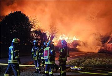 Feuerwehrleute stehen vor brennenden Häusern. Ein verheerendes Feuer in Dollern hat drei Gebäude zerstört.