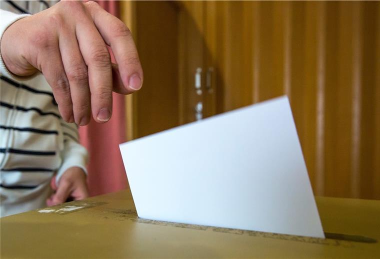 Ein Wähler schmeißt einen Zettel in eine Wahlurne.