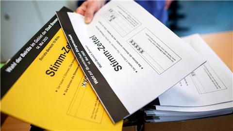 Ein Wahlhelfer gibt in einem Wahllokal die Stimmzettel für die Bürgerschaftswahl und die Kommunalwahl an die Wähler aus.