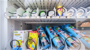 Ein Warenautomat, unter anderem mit Lachgasflaschen bestückt, steht vor einem Ladengeschäft.