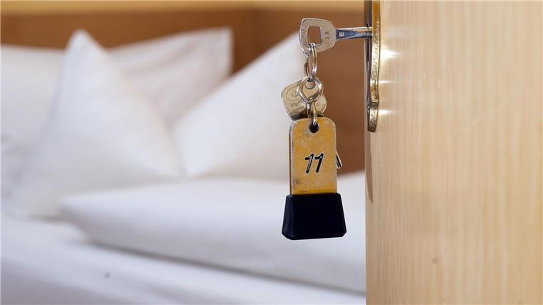 Ein Zimmerschlüssel hängt am 28.11.2014 in einem Gästehaus vor einem Bett im Türschloss.
