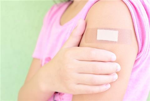 Ein Mädchen hat ein Pflaster auf dem Arm.