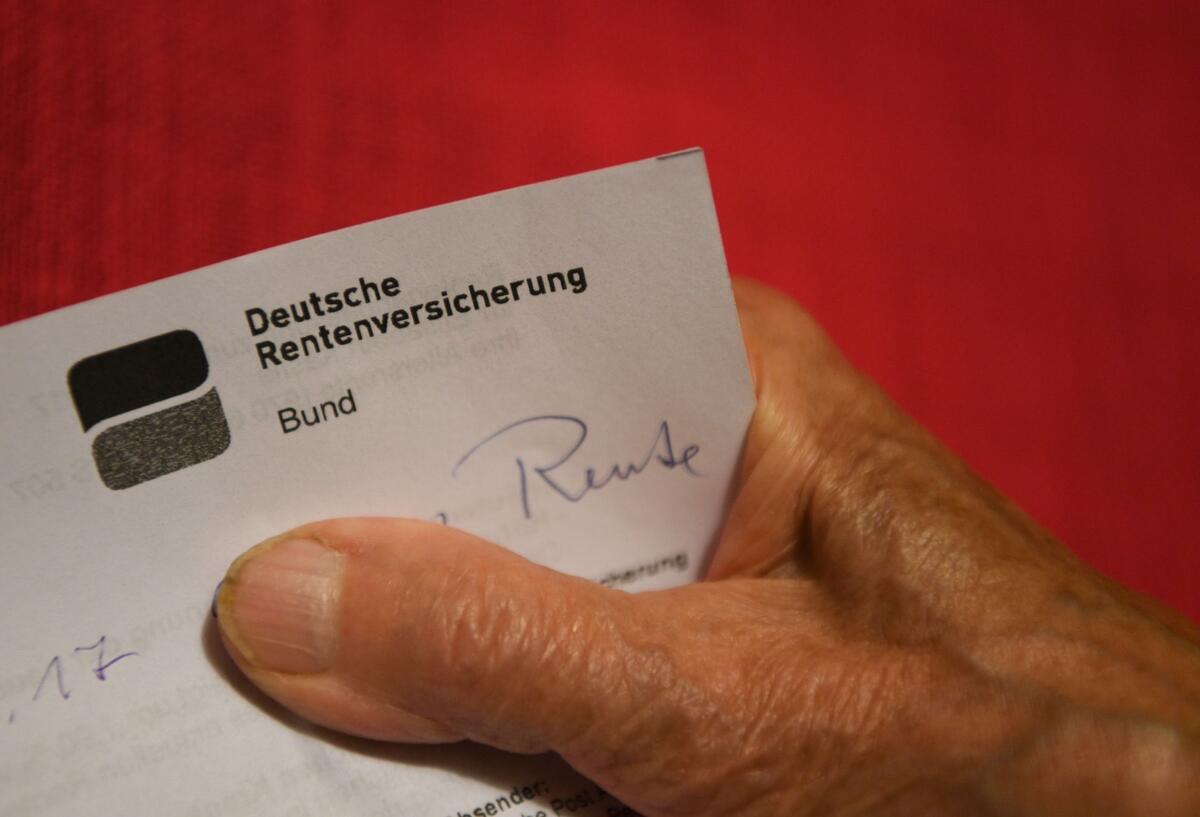 Eine ältere Frau hält ihren Rentenbescheid in der Hand.