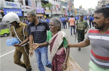 Eine ältere Frau wird in der Nähe des Explosionsort in St. Anthony's Shrine in Colombo in Sicherheit gebracht.  Bei Explosionen in Kirchen und Luxushotels in Sri Lanka sind mehrere Menschen getötet und mindestens 160 Menschen verletzt worden.
