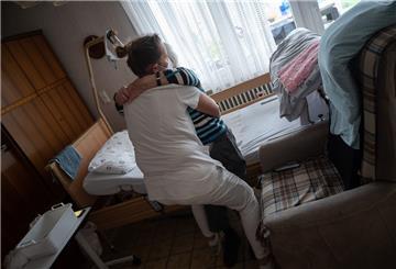 Eine ambulante Pflegerin bandagiert die Beine eines alten Mannes. Im Landkreis Rotenburg ist es zunehmend schwierig, Menschen für solche Tätigkeiten zu finden.