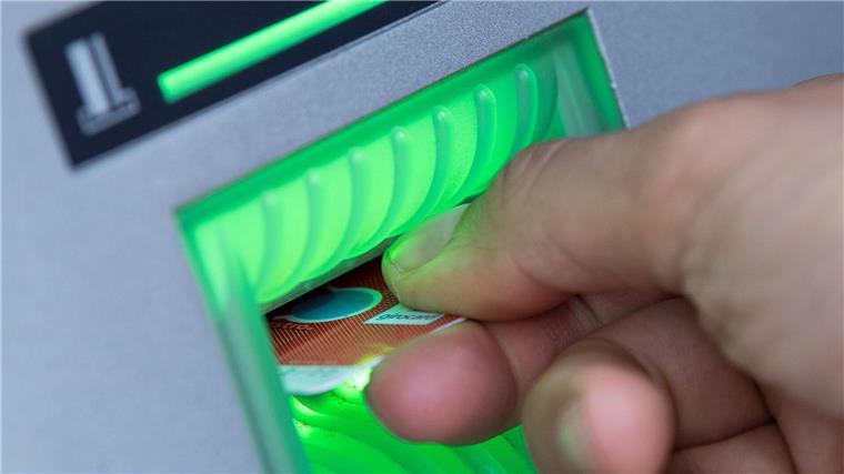 Eine Bankkundin steckt ihre Girokarte in einen Geldautomaten.