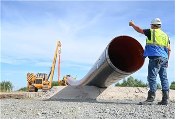 Eine Baumaschine verlegt Rohre für die LNG-Anbindung. Polier Bernd Kampen kontrolliert die Baustelle.