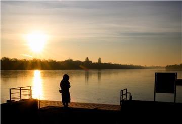 03.02.2025, Niedersachsen, Hannover: Eine Frau steht bei Sonnenaufgang am gefrorenen Maschsee. Foto: Julian Stratenschulte/dpa +++ dpa-Bildfunk +++
