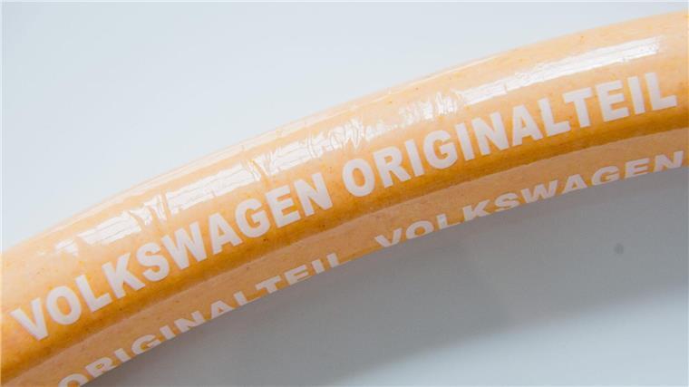 Eine Currywurst mit Aufschrift „Volkswagen Originalteil“ liegt auf einem Teller.