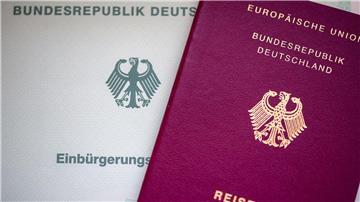 Eine Einbürgerungsurkunde der Bundesrepublik Deutschland (l) und ein deutscher Reisepass liegen auf einem Tisch.