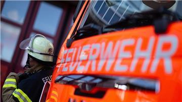 Eine Einsatzkraft der Feuerwehr steht neben einem Einsatzfahrzeug der Feuerwehr.