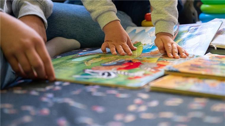Eltern fordern Entlastung für Kita-Fachkräfte Eine Erzieherin liest in einer Kita Kindern vor.