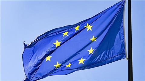 Eine Europaflagge weht vor blauem Himmel.