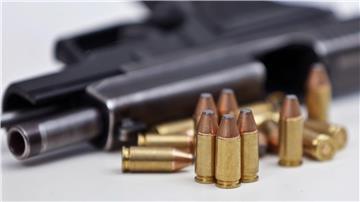Eine Faustfeuerwaffe liegt mit Magazin und Munition auf einem Tisch.
