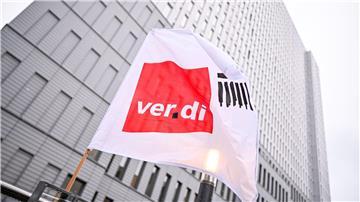 Eine Flagge von Verdi weht bei einem Warnstreik vor einem Hochhaus.