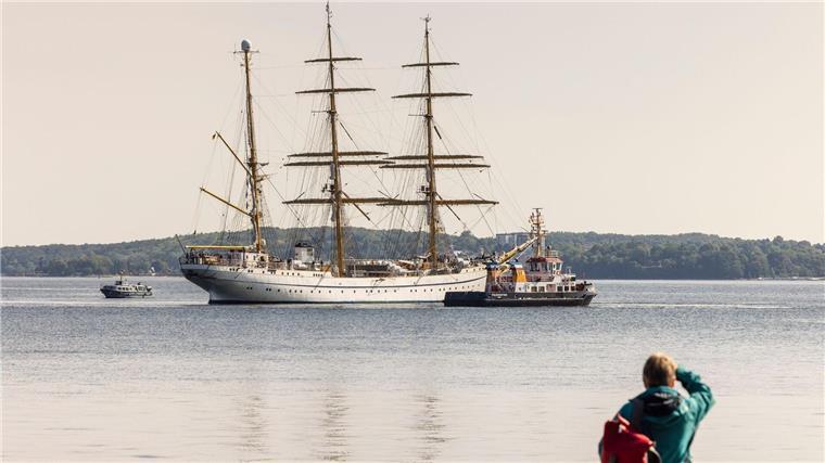 Eine Frau beobachtet vom Ufer aus die „Gorch Fock“ in der Innenförde.